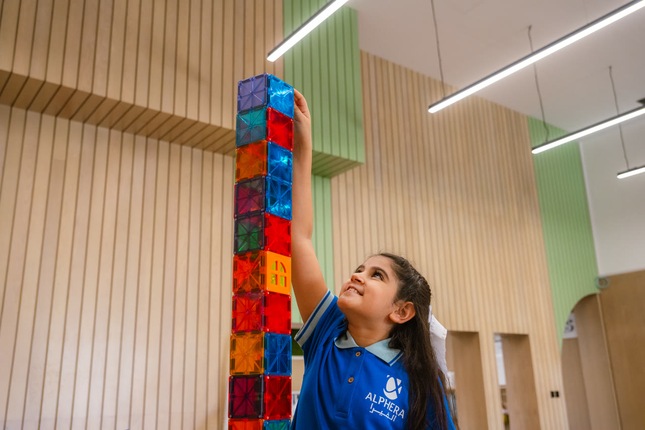 A learner builds a tall tower with magnetic tiles.